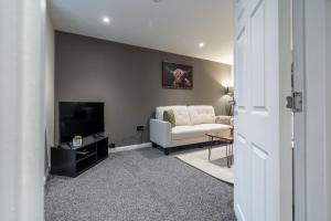 Broom Cottage في لانارك: غرفة معيشة بها أريكة بيضاء وتلفزيون