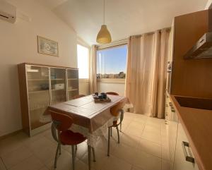 une cuisine avec une table et des chaises ainsi qu'une fenêtre dans l'établissement House Blue Roses Apartment Step Up in Puglia for your Niksen, à Bari