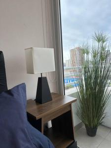 a lamp on a table next to a bed with a window at Departamento 1D1B Matiz Central in Iquique