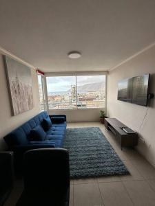 a living room with a blue couch and a large window at Departamento 1D1B Matiz Central in Iquique