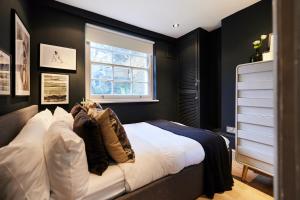 a bedroom with a bed with black walls and a window at The Myddelton Square - Cosy 1BDR Flat in London