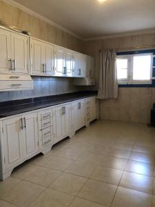 a kitchen with white cabinets and a tile floor at Das! Haus am Meer in Safaga