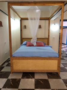 sypialnia z łóżkiem z baldachimem i podłogą wyłożoną szachownicą w obiekcie Das! Haus am Meer w mieście Safadża