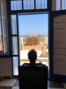 a person sitting in a chair looking at the ocean through a door at Das! Haus am Meer in Safaga