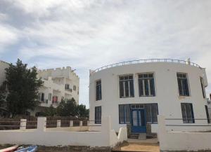 biały budynek z niebieskimi drzwiami obok dwóch budynków w obiekcie Das! Haus am Meer w mieście Safadża