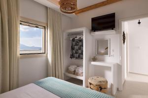 a bedroom with a bed and a window and a television at Villa Manikas Milos in Adamantas