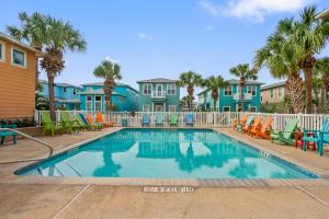 a swimming pool with chairs and palm trees at Friday Life in Port Aransas