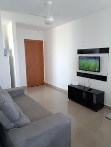a living room with a couch and a flat screen tv at Apartamento aconchegante Jd América in Maringá