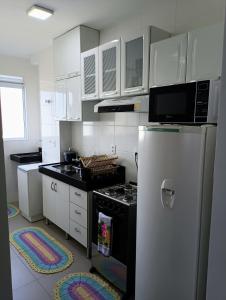 una cucina con piano cottura e frigorifero di Apartamento aconchegante Jd América a Maringá