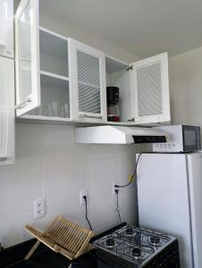 a small kitchen with a stove and white cabinets at Apartamento 5 minutos do parque de exposições in Maringá