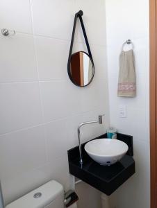 ein Badezimmer mit einem Waschbecken und einem Spiegel auf der Theke in der Unterkunft Apartamento aconchegante Jd América in Maringá