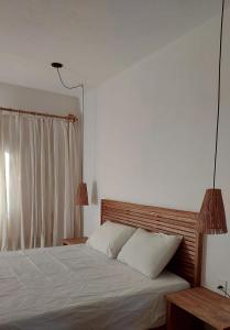 a bedroom with a bed with white sheets and two lamps at Casa Trancoso Refúgio in Trancoso