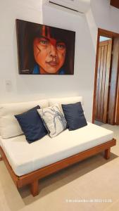 a couch with a painting of a girl on the wall at Casa Trancoso Refúgio in Trancoso