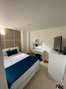 Schlafzimmer mit einem Bett und einem Schreibtisch mit einem TV in der Unterkunft Hotel Boutique Paralela Real. in Manizales