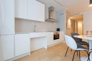 a kitchen with white cabinets and a table and chairs at Uma Suites O'Donnell in Madrid