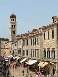 un grupo de personas caminando por una calle con una torre del reloj en Studio Apartments Stradun, en Dubrovnik