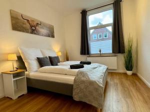 a bedroom with a bed and a large window at Charmante Altbauwohnung an der Kesselschleuse 1 in Emden