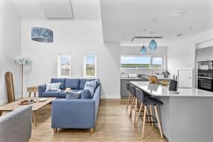 a living room with a blue couch and a kitchen at No 8 The Vista, Willingcott, Woolacombe in Woolacombe