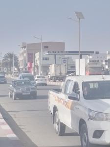 un camión blanco conduciendo por una calle de la ciudad con coches en Dar Daoudi, en Nouakchott