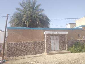 a building with a gate and a palm tree at Dar Daoudi in Nouakchott