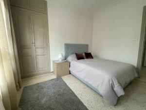 biała sypialnia z łóżkiem i stolikiem nocnym w obiekcie Ideal location in the heart of L’hivernage w Marakeszu