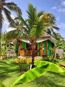 une maison avec un palmier en face dans l'établissement Côco Verde Chalé - Icaraí Kite Village, à Icaraí
