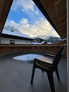 a chair sitting on a patio with snow covered mountains at Martins Apartmenthaus in Biberwier