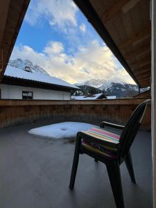 una silla sentada en un patio con montañas cubiertas de nieve en Martins Apartmenthaus en Biberwier