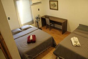 1 dormitorio con 2 camas y escritorio con ventilador en AP 40- Apart OH, en Ciudad del Este