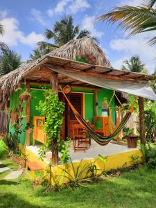 une maison verte avec un hamac en face de celle-ci dans l'établissement Côco Verde Chalé - Icaraí Kite Village, à Icaraí