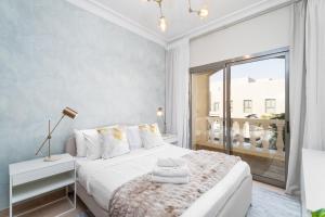 1 dormitorio con cama blanca y ventana grande en Nasma Luxury Stays - Jaw-dropping 4BR Villa with Calming Golf View en Ras al-Khaimah