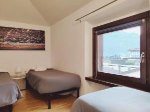 um pequeno quarto com 2 camas e uma janela em King Of The Lake em Riva del Garda
