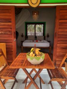 a bowl of fruit on a wooden table with two chairs at Côco Verde Chalé - Icaraí Kite Village in Icaraí
