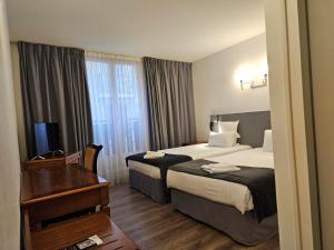 エヴィアン・レ・バンにあるホテル ル ブルゴーニュのベッド2台とデスクが備わるホテルルームです。
