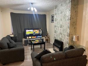 a living room with two couches and a flat screen tv at Five Oaks House- Entire 3 Bedroom House for Family & Contractors with up to 5 sleep- NO PARTIES ALLOWED in Willenhall