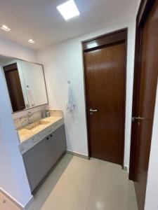 a bathroom with a sink and a wooden door at Apartamento em João Pessoa (Miramar) in João Pessoa
