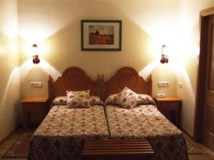 a bedroom with a bed with two lamps on the wall at Hotel Turrull in Vielha