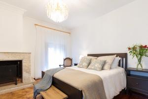 a bedroom with a bed with a fireplace and a chandelier at Camiño Ancho casa rural in Pobra do Caramiñal