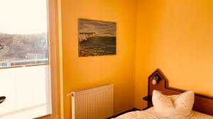 ein Schlafzimmer mit einer orangefarbenen Wand mit einem Bett und einem Fenster in der Unterkunft Haus Am Strand in Breege