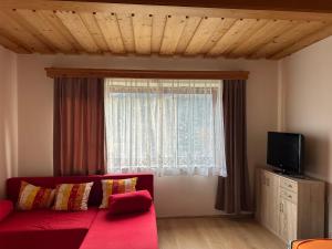 sala de estar con sofá rojo y ventana en Sissi Apartment en Ausserfragant