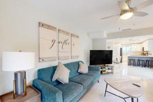 sala de estar con sofá azul y TV en Gather Together - Unit 145, en Marco Island