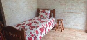 a bed with a red and white comforter and a stool at Chalé das Orquídeas in Monte Verde