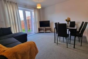 a living room with a couch and a table with chairs at A modern and spacious home. in Luton