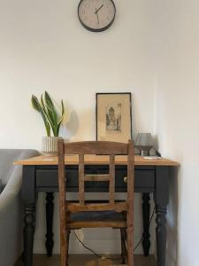 a desk with a chair and a clock on the wall at Guest Homes - Fairlie Flat in Oxford