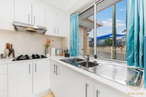 a white kitchen with a sink and a window at Hurstville 2Br Granny flat near Shopping & Train in Sydney