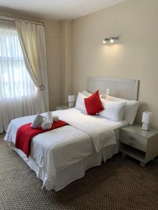 a bedroom with a large bed with red and white pillows at Hotel Thule in Windhoek