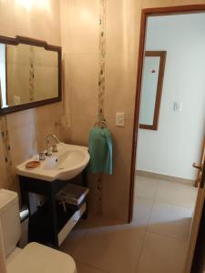 Un baño con lavabo, inodoro y espejo. en RS Las Grutas, en Las Grutas