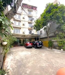 two cars parked in a parking lot in front of a building at Hong Ha Airport Hotel in Thach Loi