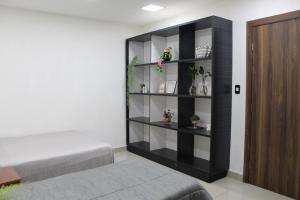 a bedroom with a black book shelf next to a bed at AP 80- Apart OH in Ciudad del Este