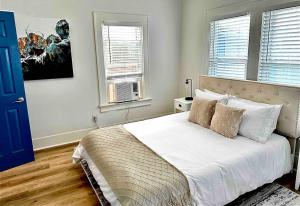 a bedroom with a bed with white sheets and windows at Luxury 1 Bd Montrose - Genova at The Italian Plaza in Houston